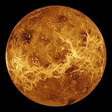 A false color image of Venus: Ribbons of lighter color stretch haphazardly across the surface. Plainer areas of more even colouration lie between.