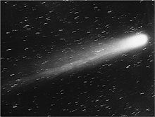 Black-and-white photograph of the comet, its nucleus brilliant white, and its tail very prominent, moving up and to the right